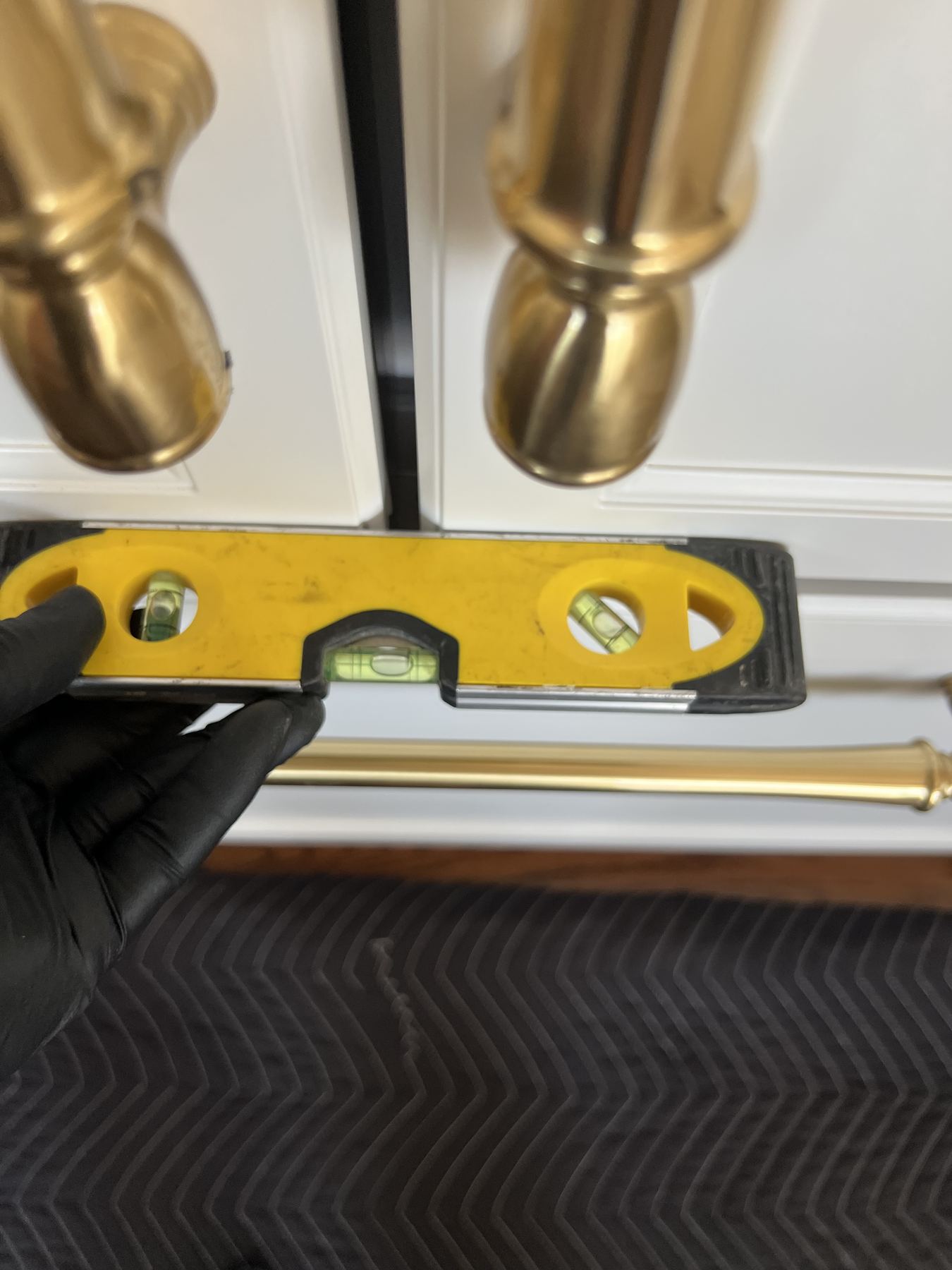 Technician checking door alignment with a level against brass handles