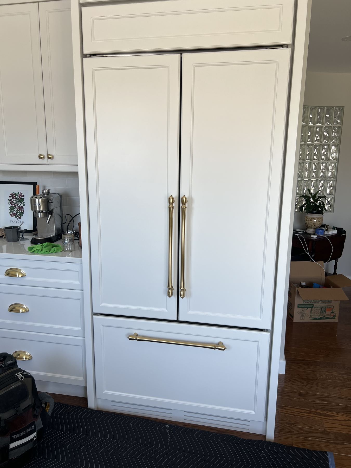 Panel-ready Sub-Zero refrigerator with brass handles in a white kitchen